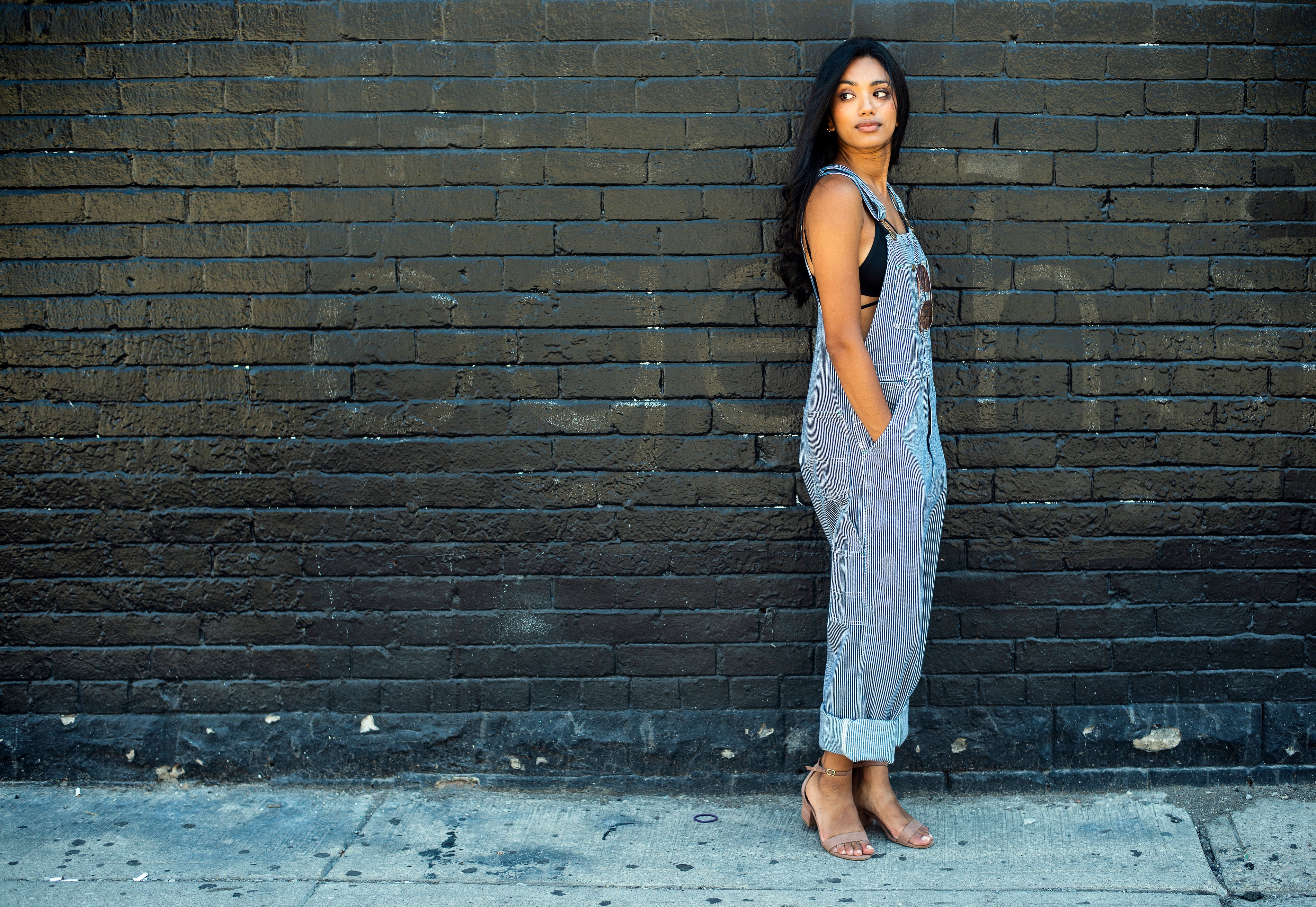 files/woman-in-overalls-poses-by-brick-wall.jpg